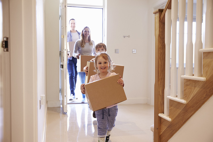 Family carrying boxes into a house